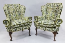 A pair of Queen Anne style wingback armchairs, with out-scrolled arms and shell carved walnut