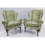 A pair of Queen Anne style wingback armchairs, with out-scrolled arms and shell carved walnut