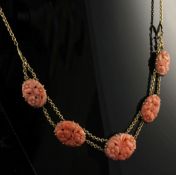 A 1920's 15ct gold and coral necklace, set with five graduated oval coral panels carved with