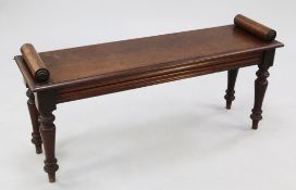 A Victorian mahogany window seat, with cylindrical turned ends and cushion moulded frieze, on