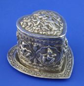 An early 20th century Indian silver heart shaped box and cover, embossed with deities amongst