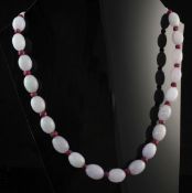 A single strand graduated oval jadeite bead necklace, with facet cut ruby bead spacers, 18in.