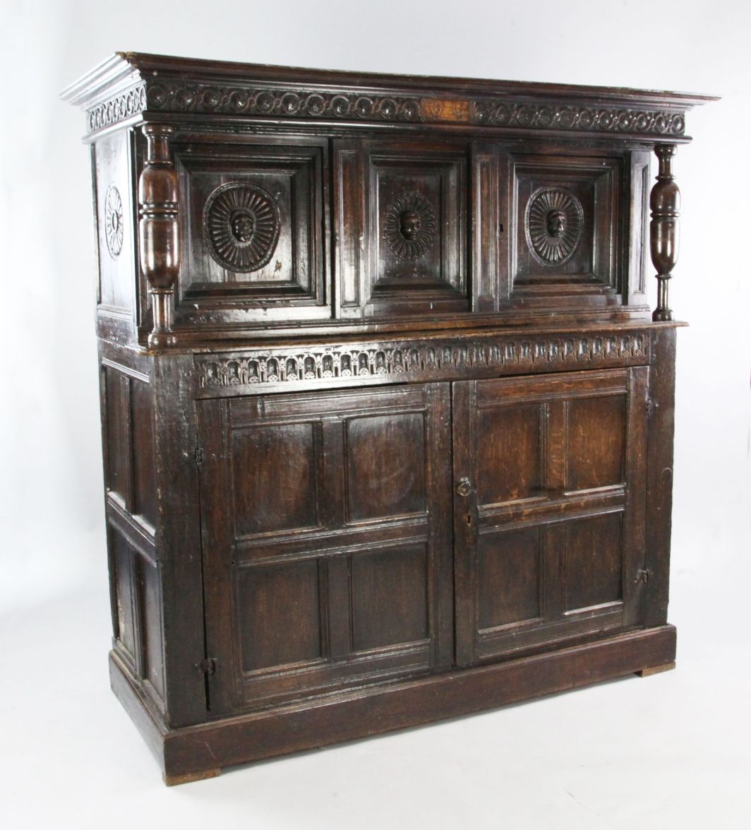 A 17th century carved oak court cupboard, with the date 1611 and initials WW, with cup and cover