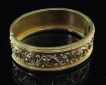 A Victorian gold hinged bracelet, decorated with tulip heads amongst scrolling foliage, lacking