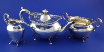 An Edwardian Scottish silver three piece tea set, of oval form, with engraved monogram, cast foliate