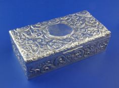 An Edwardian embossed silver rectangular cigarette box, with engraved monogram and decorated with