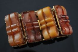 An early 20th century 9ct gold mounted amber bracelet, with gilt metal clasp and seven scroll carved