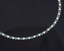 An 18ct white gold, emerald and diamond line bracelet, set with twenty three round cut diamonds