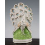 An unusual Staffordshire pottery flatback peacock figure, mid 19th century, the plumage of the