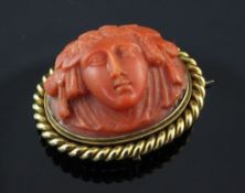 A late 19th century gold mounted coral brooch, carved with the head of a lady, with rope twist