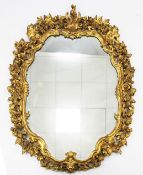 A pair of carved giltwood and gesso cartouche shaped wall mirrors, with pierced floral and C