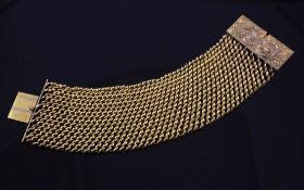 An early 19th century gilt metal mesh link bracelet, with rectangular clasp engraved with scrolls,