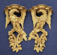 A pair of 18th century carved giltwood wall brackets, each modelled as an eagle with outstretched