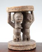 A Yoruba carved wood stool, modelled with male and female figures, height 11in.