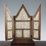 An early 20th century hardwood folding triptych, mounted with ten carved ivory panels depicting