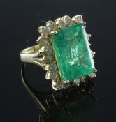 A large 14ct gold emerald and diamond rectangular cluster ring, with central 14.57ct emerald