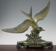 A French Art Deco patinated metal model of a sea bird, on a rocky outcrop with lapping waves