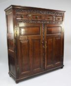 A William III carved oak parlour cupboard, with scrolling leaf frieze above two single drawers above