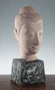 A large Thai sandstone Buddha head, on a tapering square section plinth painted to simulate