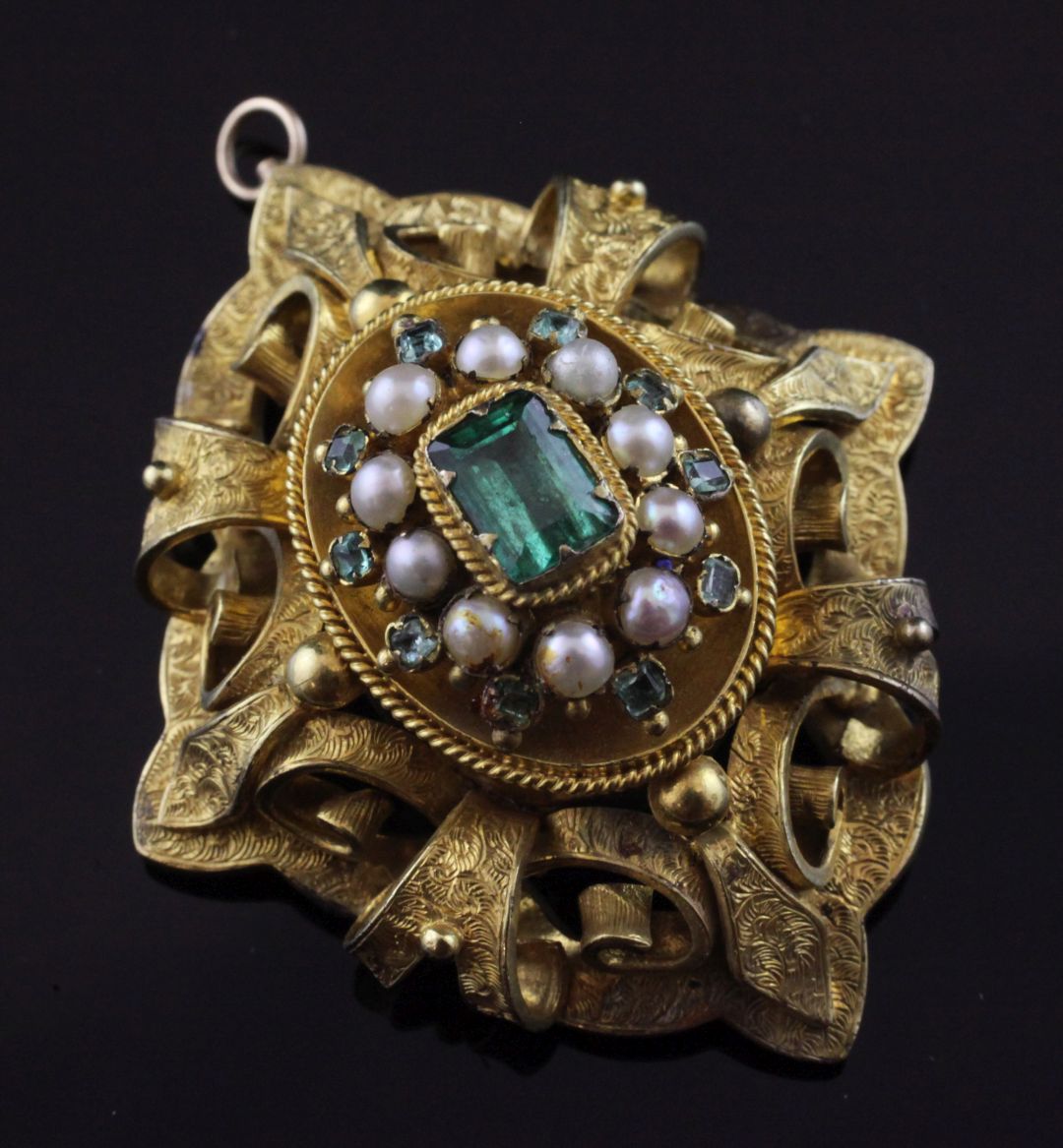 A Victorian gold, emerald and split pearl set oval brooch, with engraved pierced scroll mount and
