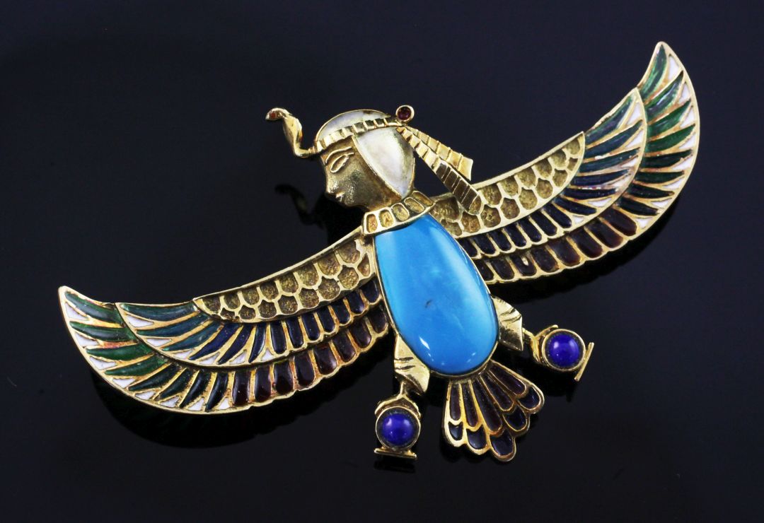 An Egyptian revival gold, plique a jour, turquoise and lapis lazuli winged falcon brooch with the