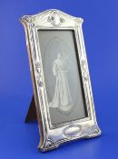 An Edwardian Art Nouveau repousse silver photograph frame, of shaped rectangular form, with stylised