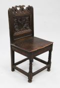 A carved oak back stool, c.1700, with pierced scrolling crest rail above a single panelled back
