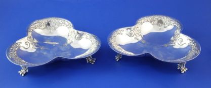 A pair of early 20th century silver trefoil shaped bonbon dishes, with embossed foliate scroll