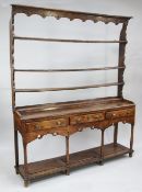 A George III oak Welsh dresser, with open plate rack above three frieze drawers with pierced