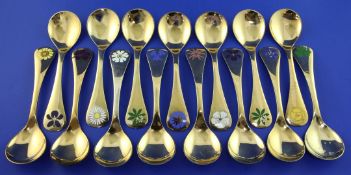 Fourteen Georg Jensen silver gilt and enamel annual spoons, each terminal with foliate decoration,