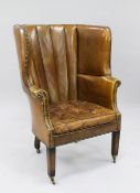 A George III style porter's chair, with rounded back and brass studded brown leather upholstery,