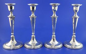A set of four Edwardian silver candlesticks, of panelled tapering form, with engraved decoration,