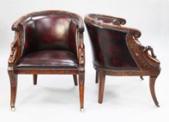 A pair of French Empire style carved mahogany and brass studded leather tub shaped armchairs, with