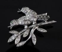 A white gold, diamond and garnet brooch, modelled as two birds on a branch, set with round and