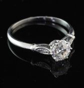 A platinum and single stone diamond ring with diamond set shoulders, the central stone weighing