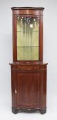 An Edwardian inlaid mahogany serpentine corner cabinet, with single glazed door above single