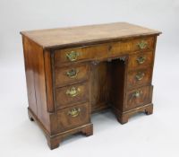 A George II walnut and crossbanded kneehole desk, fitted with central recessed cupboard door and