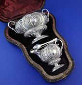 A cased late Victorian silver cream and sugar set with tongs, of oval form, embossed with foliate