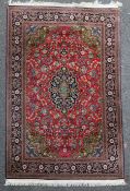 An Isfahan rug, with pole medallion and field of scrolling foliage, on a coral red ground, with