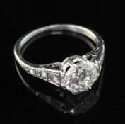 A platinum and single stone diamond ring, with diamond set shoulders and central stone weighing