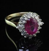An 18ct gold, ruby and diamond oval cluster ring, the oval cut ruby weighing approximately 1.50-2.