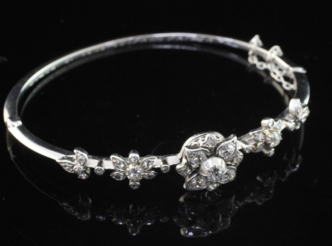 An early 20th century white gold and diamond hinged bangle, with five foliate motifs set with old