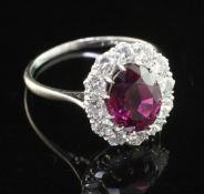 An 18ct white gold and platinum, ruby and diamond cluster ring, of oval form, the central oval cut