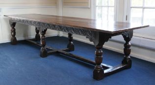 A large carved oak refectory table, the plank top with cleated ends and lunette carved frieze,