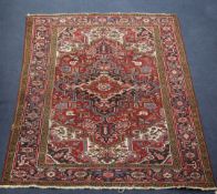 A Heriz rug, with central medallion within a field of geometric motifs, on a red ground, with