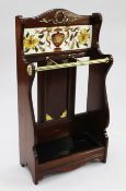A late Victorian walnut and brass mounted umbrella stand, the arched back with polychrome printed