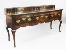 A George III oak dresser base, the shallow back fitted with five shaped drawers above three frieze