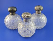 Three early 20th century silver lidded cut glass globular scent bottles, two with repousse lids