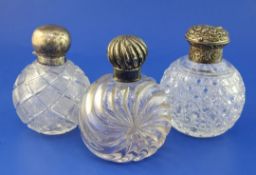 Three late Victorian silver lidded cut glass globular scent bottles, two with hinged lids and one