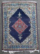 A Persian rug, with central stepped foliate medallion, on a deep blue ground, with three row